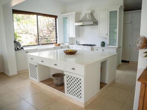 a white kitchen with a large island in the middle at Oniro Guest House in Bedfordview