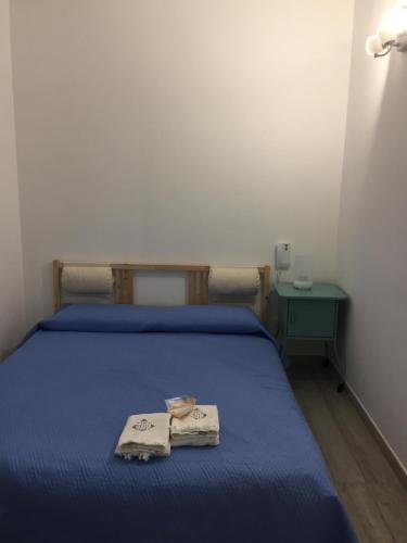 a bedroom with a bed with blue sheets and a table at Villa Atena Baia Cornino in Custonaci