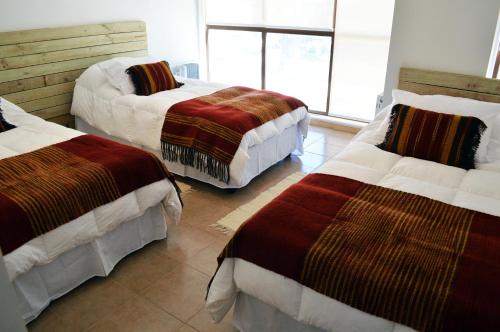 a room with three beds with blankets on them at Apart Hotel Endurance in Punta Arenas
