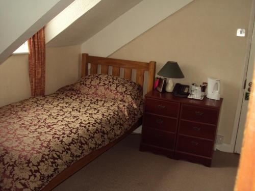 a bedroom with a bed and a dresser with a lamp at Mountbatten Hotel in Plymouth