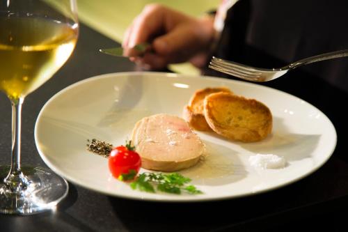 a white plate with food and a glass of wine at Hôtel Oceania Le Métropole in Montpellier