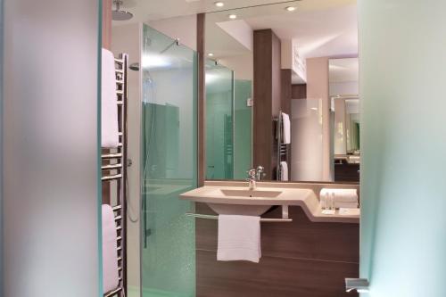 a bathroom that has a sink and a shower in it at Hôtel Oceania Le Métropole in Montpellier