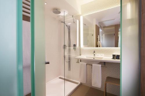 a bathroom with a shower and a sink at Hôtel Oceania Le Métropole in Montpellier