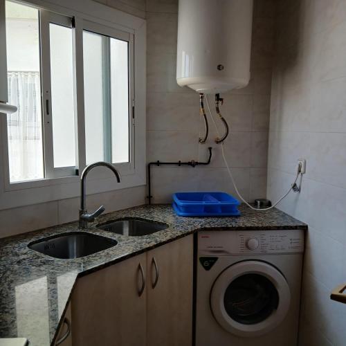 a kitchen with a sink and a washing machine at Mar y Sol in Calafell