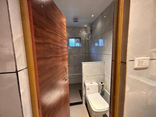 a bathroom with a toilet and a wooden door at Gokarna City Guest House in Gokarna