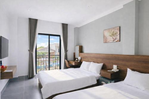 a hotel room with two beds and a balcony at Hoa Dã Quỳ Hotel in Pleiku