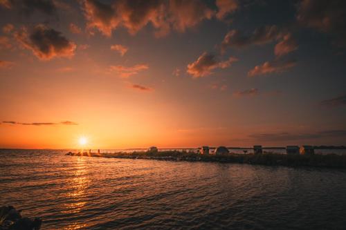 a sunset over the ocean with the sun setting at Marina Martinshafen - Beach life in Sassnitz