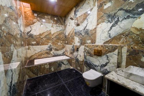 a stone bathroom with a toilet and a sink at Lumira Queensbury Villa in Udaipur