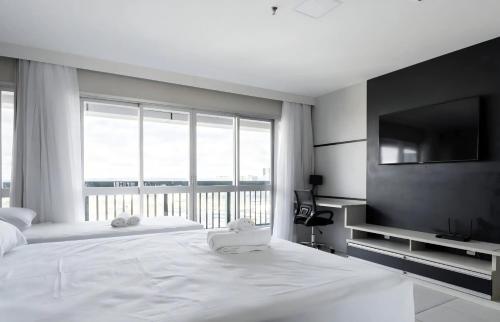 a bedroom with a large white bed and a large window at Flat com vista espetacular no centro de Brasília Vision Work and live in Brasília