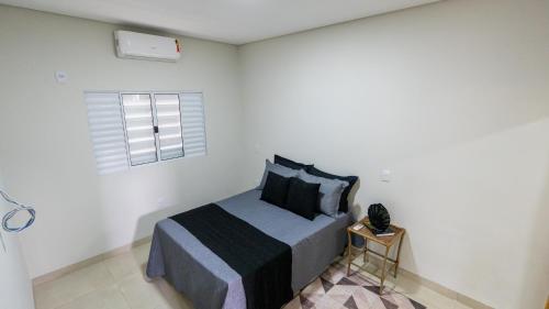 a white bedroom with a bed and a window at Jahu Center Casas Un 5 in Jaú