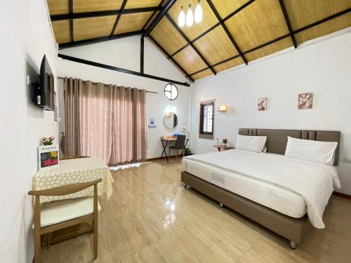 a bedroom with a bed and a table and a chair at โรงแรมสบายดีรีสอร์ท in Tha Bo