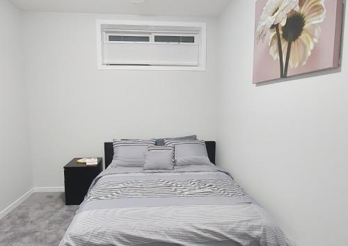 a white bedroom with a bed and a window at Cozy Luxe Suites in Calgary