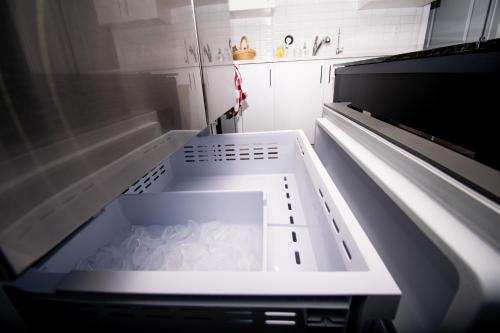 an empty refrigerator with its door open in a kitchen at Cozy Luxe Suites in Calgary