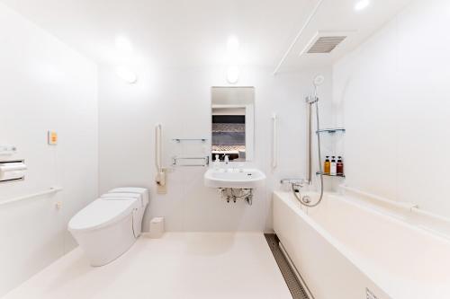 a white bathroom with a toilet and a sink at The OneFive Osaka Shinsekai in Osaka