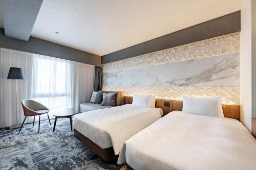 a hotel room with two beds and a couch at The OneFive Osaka Shinsekai in Osaka
