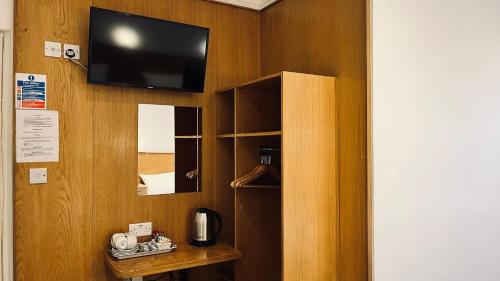 a room with a tv and a wooden wall at West Cromwell Hotel in London