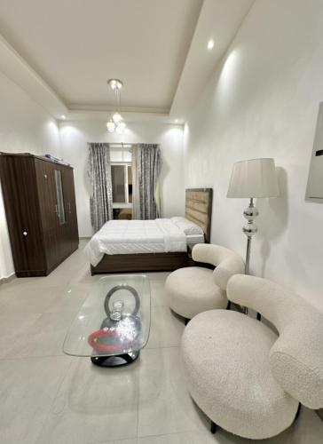 a bedroom with a bed and two chairs and a table at Entire Studio Apartment with King Bed in Ajman 