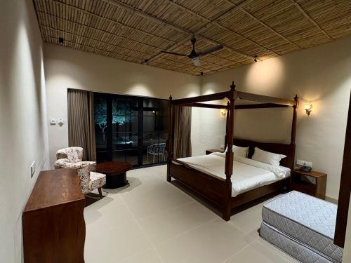 a bedroom with a canopy bed and a chair at Jalsa Jawai Resort in Bīsalpur