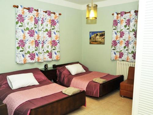 a bedroom with two beds and curtains and a chair at Beit Wadih in Ghazīr