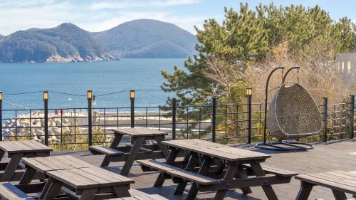 a group of picnic tables on a deck overlooking the water at Geoje Badageurigo Pension in Geoje