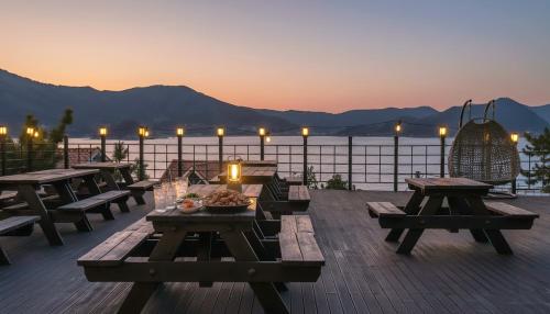 a deck with picnic tables and a view of the water at Geoje Badageurigo Pension in Geoje