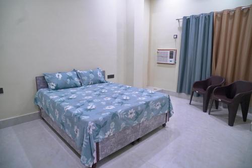 a bedroom with a bed in a room with chairs at Narayan Homestay & Guest House in Haridwār