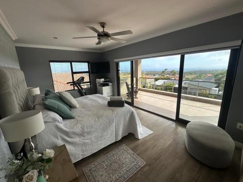 a bedroom with a bed and a large window at Chasing Jacuzzi Sunsets sea and mountain views in Hermanus