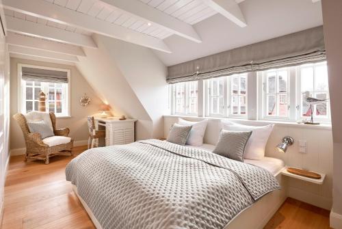 a bedroom with a bed and a chair and windows at Wiesen Engel in Oldsum