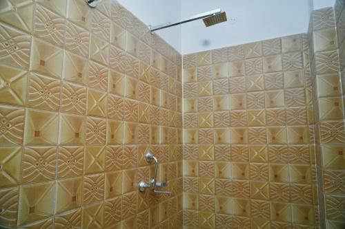a bathroom with a shower with a tiled wall at Narayan Homestay & Guest House in Haridwār