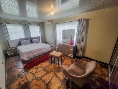 a bedroom with a bed and a chair and window at Agreste Homes in Kasama