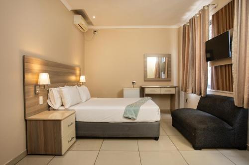 a hotel room with a bed and a chair at Tudor House Hotel in Durban