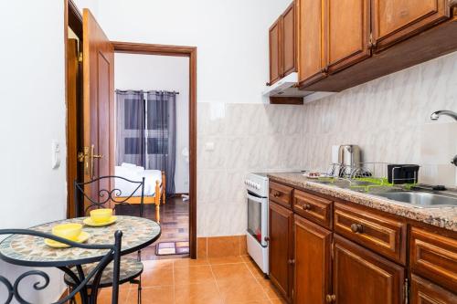 a kitchen with a table and a sink and a stove at GuestReady - Funchal Hideaway with BBQ in Funchal