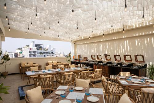 a restaurant with tables and chairs and a large window at Luxuria Varanasi By Moustache in Varanasi
