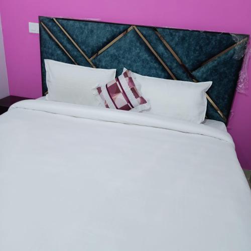 a large bed with white pillows in a purple room at AG Hotel in Zirakpur
