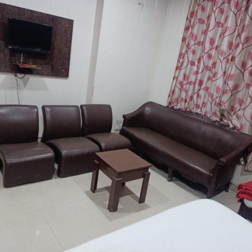 a waiting room with a leather couch and a table at AG Hotel in Zirakpur