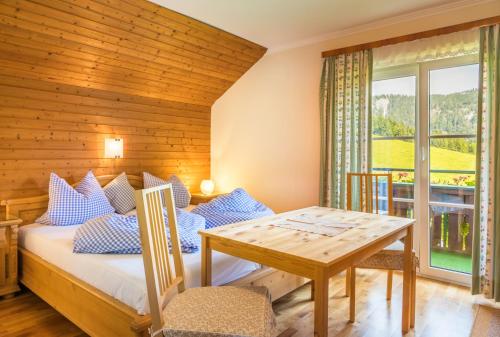 a room with a bed and a table and a window at Bambichl Hoamat in Fuschl am See