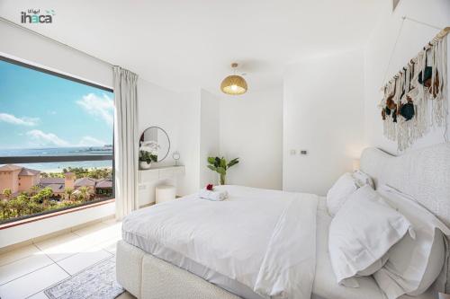 a white bedroom with a bed and a large window at 1 Br Boho Beach Ain Full Sea View JBR 1 min in Dubai