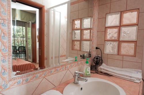 W łazience znajduje się umywalka i lustro. w obiekcie Suites Oliveri Viale Marconi w Rzymie