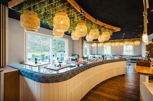 ein Restaurant mit Tischen, Stühlen und Kronleuchtern in der Unterkunft Hotel Mukran in Sassnitz