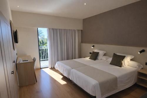 a bedroom with a large white bed and a balcony at Hotel Tanit in Benidorm