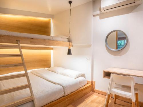a bedroom with bunk beds and a desk and a ladder at The Goose House Ubon in Ban Na Khwai