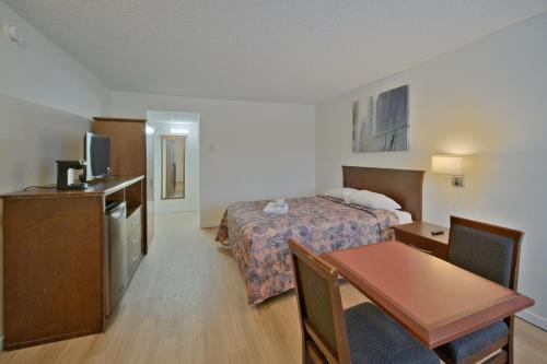 a hotel room with a bed and a table at MXP Special Rooms in Saskatoon