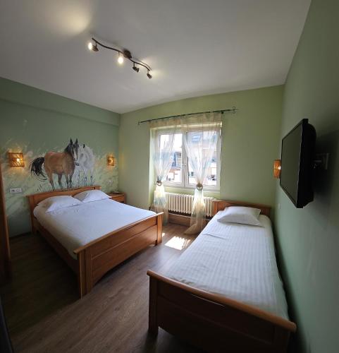 a bedroom with two beds and a window with a horse on the wall at Hotel Champ Alsace in Haguenau