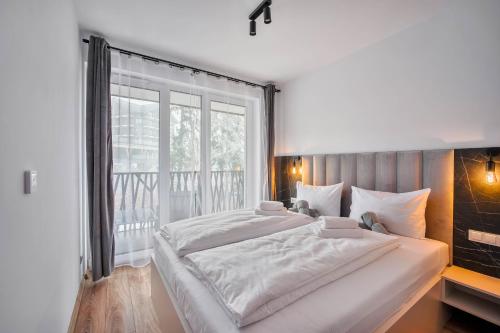 a bedroom with two beds and a large window at Dolina Szczęścia Apartamenty Pine - Dream Apart in Szklarska Poręba
