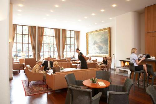 a living room filled with people sitting around a table at Hotel Baseler Hof in Hamburg