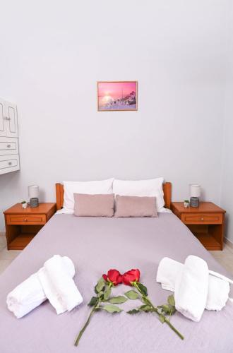 a bed with towels and a red rose on it at Efrosini & Ioanna Apartment in Ligaria