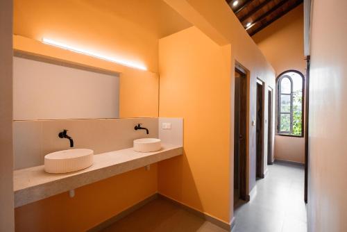 two sinks in a bathroom with orange walls at Lucky U Hostel in Ahangama