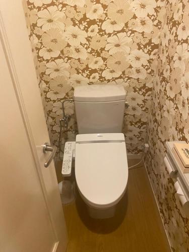 a white toilet in a bathroom with floral wallpaper at ホテルラブリー淡路島 in Sumoto