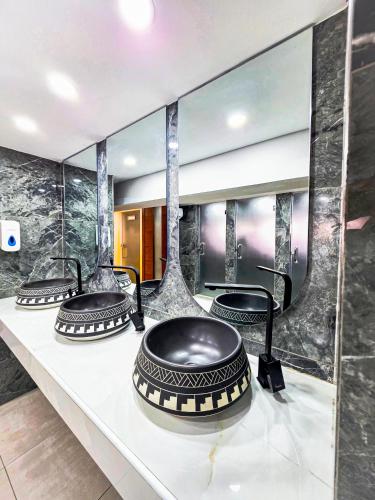 a bathroom with three sinks and a large mirror at Hotel Sapphire in Mombasa