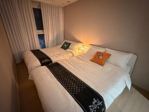 two twin beds in a room with a window at 해변1분 숙소 광안이즘, 1 min to beach Gwangan-ism in Kwangan-dong